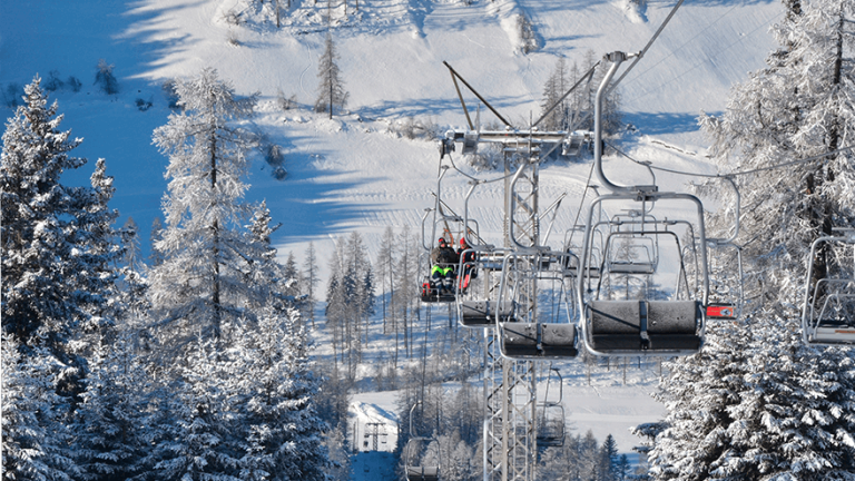 Sesselbahn Bergün–Darlux transportiert Schlittler mit ihren Schlitten über den verschneiten Winterwald
